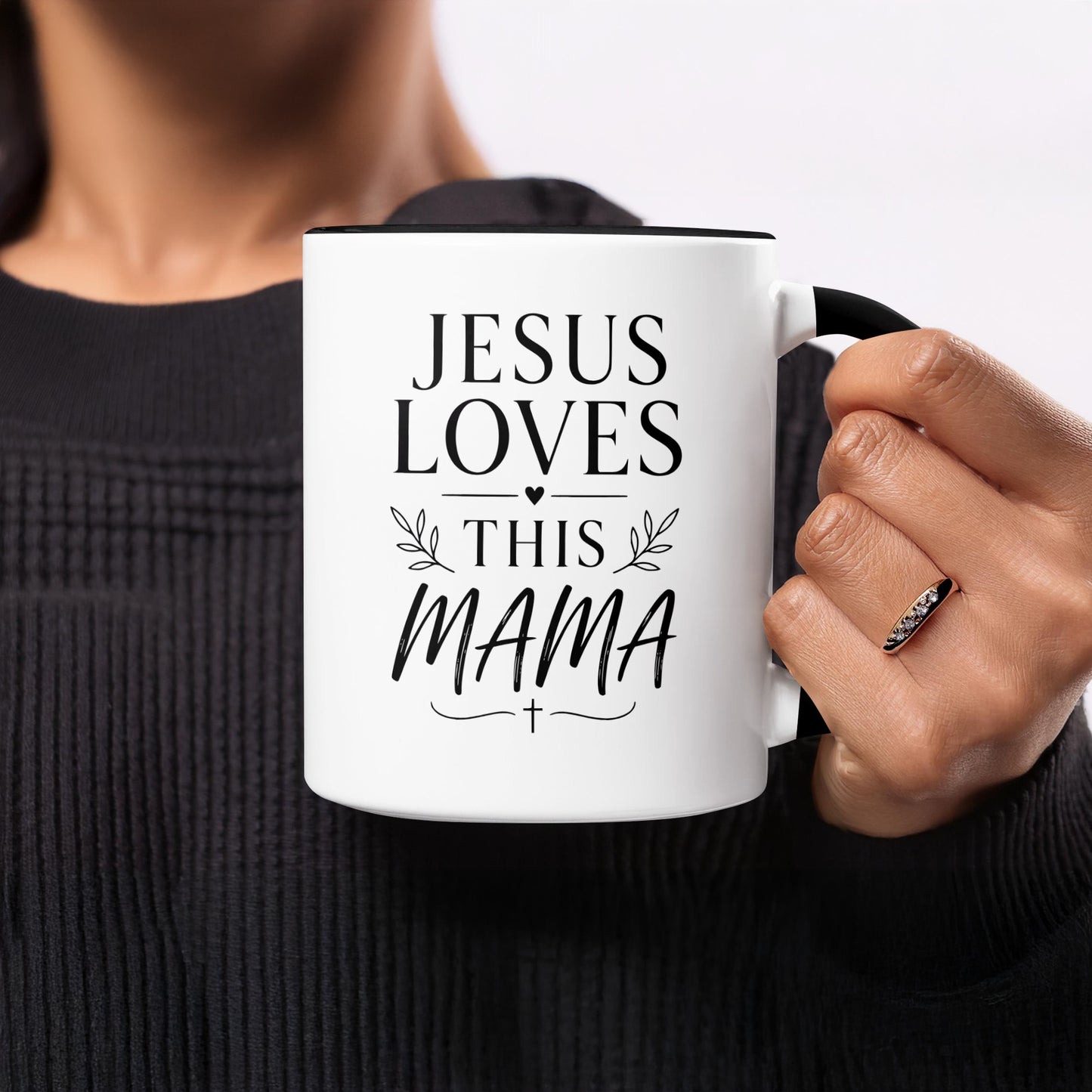 White mug with black rim, black text "JESUS LOVES THIS MAMA" and cross.